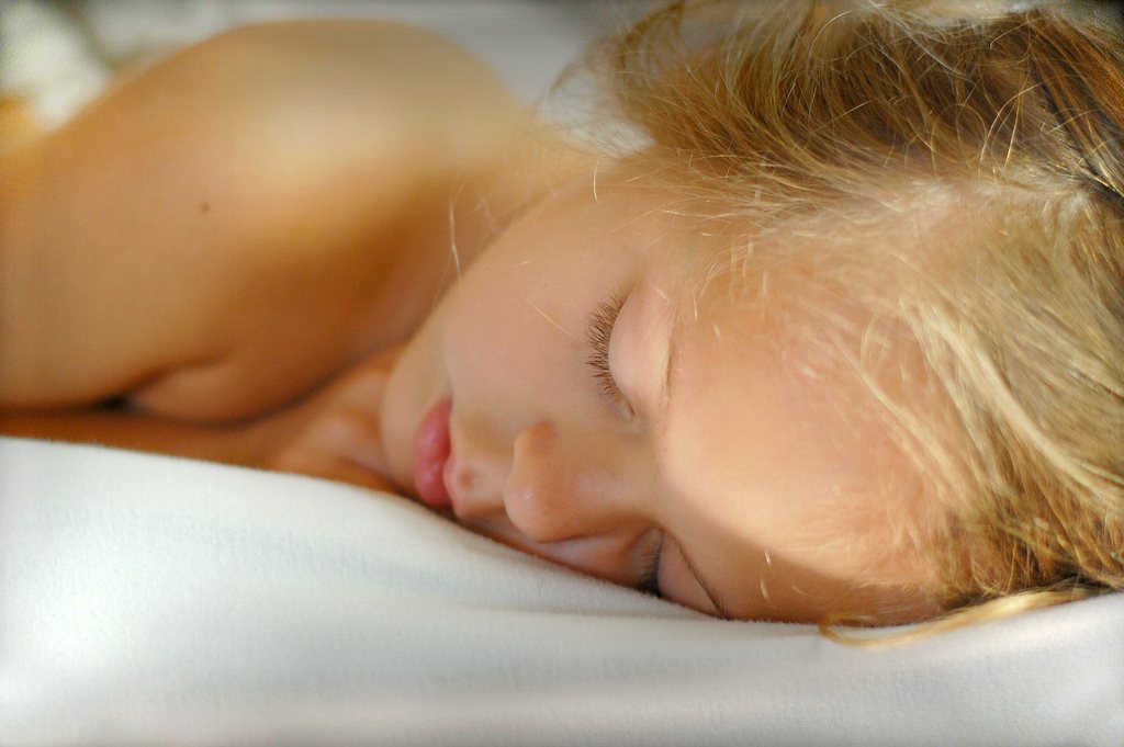 Persona durmiendo tranquilamente en una cama con sábanas blancas