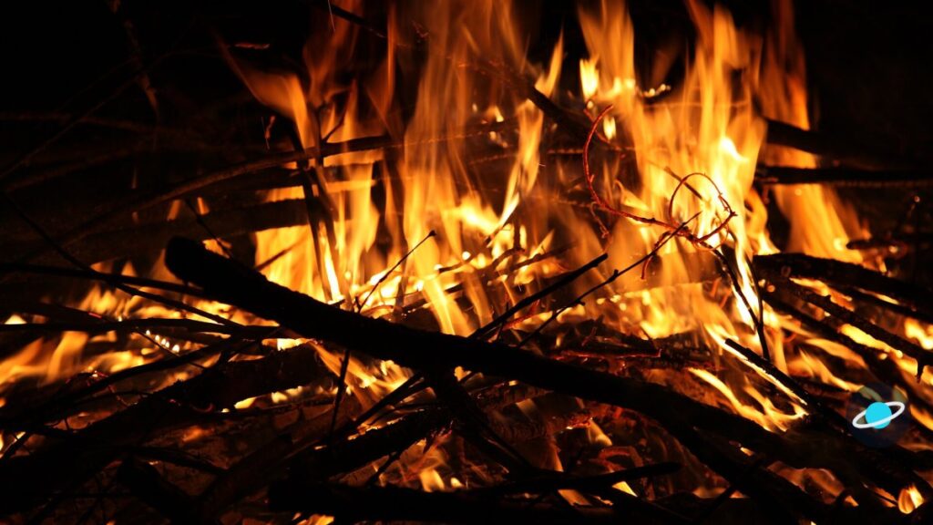 Hoguera encendida con troncos de leña y llamas altas